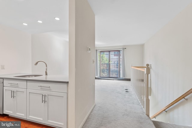 hallway with light carpet and sink