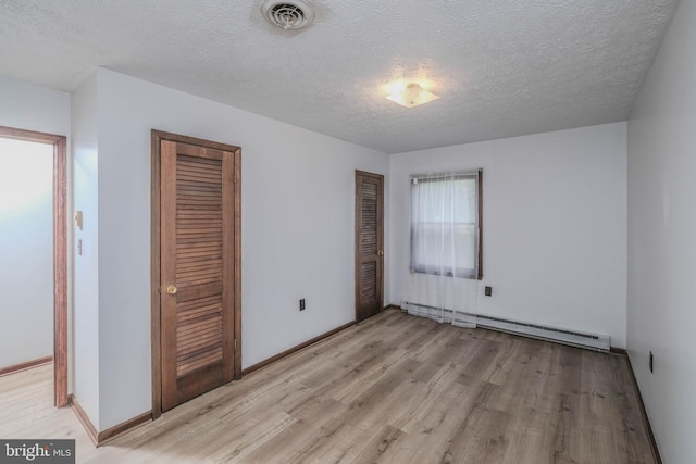 unfurnished bedroom with light wood-type flooring, a baseboard radiator, and a textured ceiling