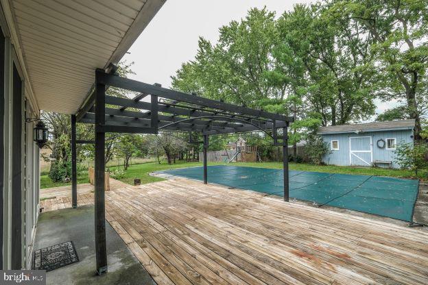 view of pool featuring a shed, a wooden deck, and a pergola