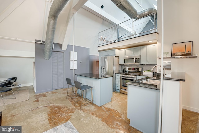 kitchen with stainless steel appliances, sink, a kitchen breakfast bar, pendant lighting, and a high ceiling