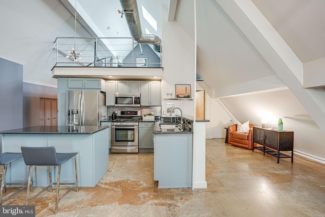 kitchen with appliances with stainless steel finishes, a kitchen breakfast bar, an inviting chandelier, a towering ceiling, and gray cabinets