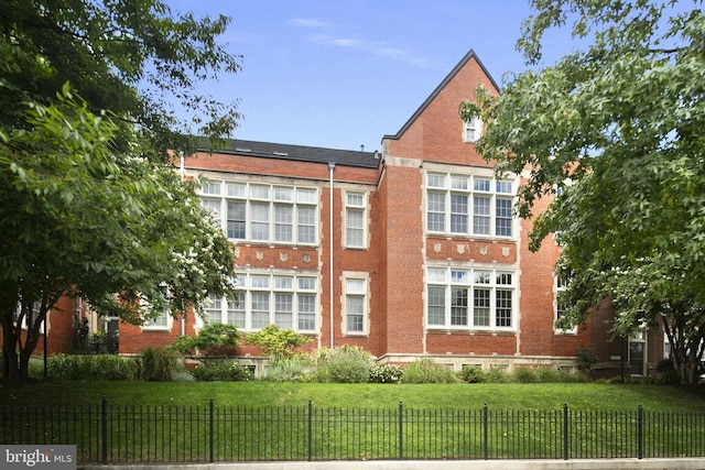 exterior space featuring fence private yard, brick siding, and a lawn