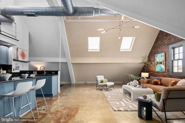 living room with high vaulted ceiling, brick wall, concrete floors, a skylight, and baseboards