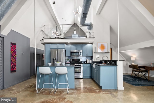 kitchen with dark countertops, appliances with stainless steel finishes, blue cabinets, an inviting chandelier, and concrete flooring