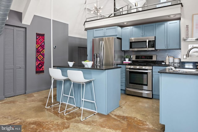 kitchen with a breakfast bar area, blue cabinets, a high ceiling, stainless steel appliances, and backsplash