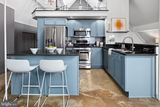 kitchen with a breakfast bar area, stainless steel appliances, a kitchen island, a sink, and decorative backsplash