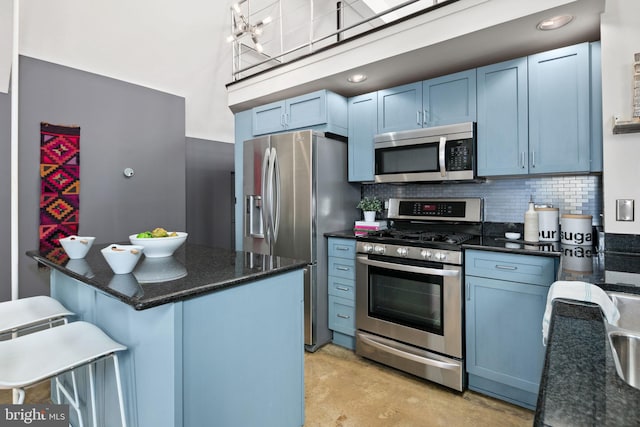 kitchen with appliances with stainless steel finishes, a breakfast bar, blue cabinetry, and decorative backsplash