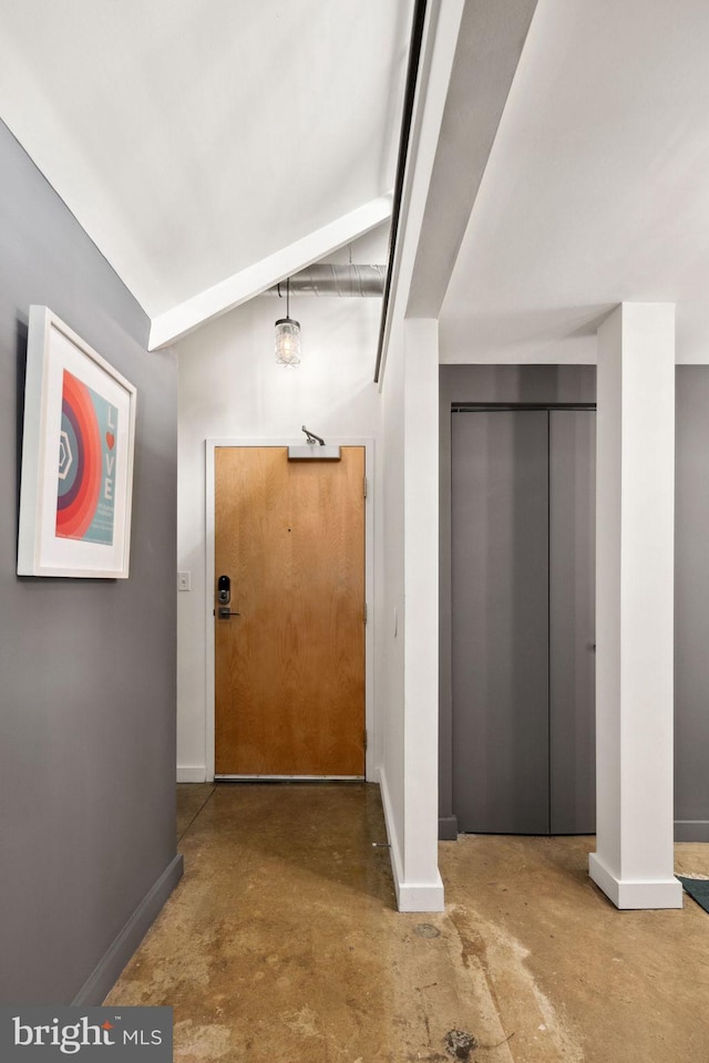 entryway featuring baseboards, unfinished concrete floors, vaulted ceiling, and elevator