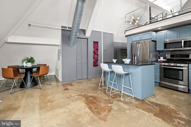 kitchen with a breakfast bar area, dark countertops, a towering ceiling, an inviting chandelier, and appliances with stainless steel finishes