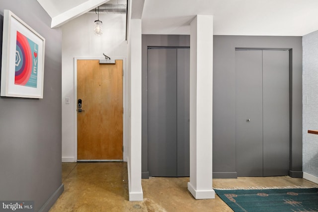 entrance foyer featuring concrete flooring, elevator, and baseboards