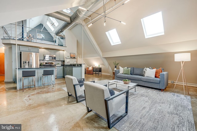 living room featuring a chandelier, sink, a skylight, and high vaulted ceiling