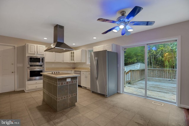 kitchen with island range hood, ceiling fan, appliances with stainless steel finishes, white cabinets, and a center island