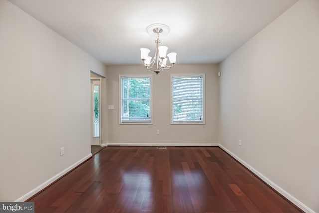 empty room featuring dark hardwood / wood-style flooring and a chandelier