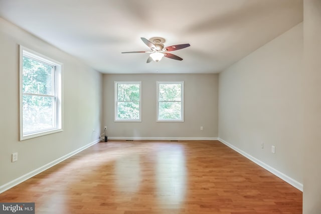 spare room featuring ceiling fan, light hardwood / wood-style flooring, and a healthy amount of sunlight