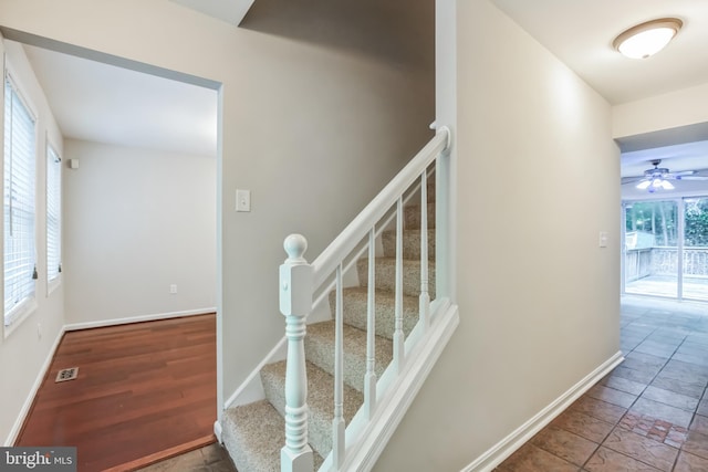 stairs with ceiling fan, plenty of natural light, and tile patterned floors