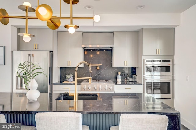 kitchen featuring a breakfast bar area, decorative backsplash, hanging light fixtures, and appliances with stainless steel finishes