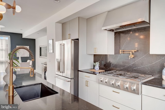 kitchen with decorative backsplash, stainless steel appliances, sink, wall chimney range hood, and white cabinetry