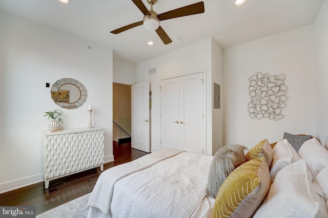 bedroom featuring dark hardwood / wood-style flooring, a closet, ceiling fan, and electric panel