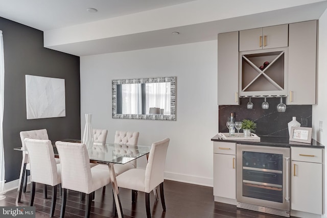 dining space featuring bar area, dark wood-type flooring, and beverage cooler