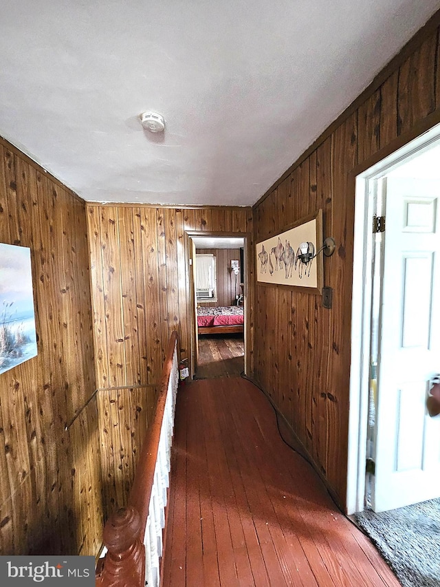 corridor with wood walls, dark hardwood / wood-style flooring, and a textured ceiling