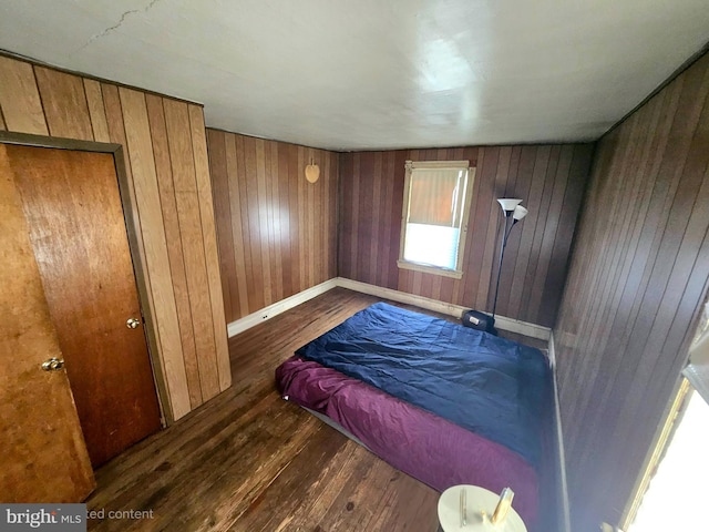 bedroom featuring wooden walls and dark hardwood / wood-style floors