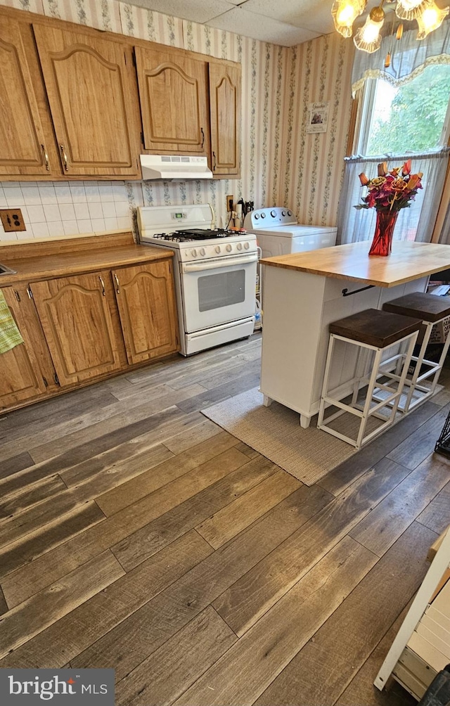 kitchen featuring washer / dryer, decorative backsplash, dark hardwood / wood-style floors, and white gas range oven