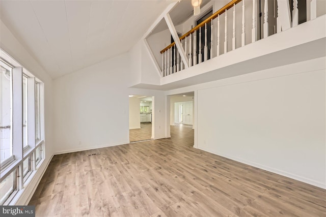 unfurnished living room featuring light wood-type flooring and high vaulted ceiling