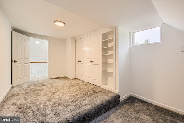 unfurnished bedroom with vaulted ceiling and dark colored carpet