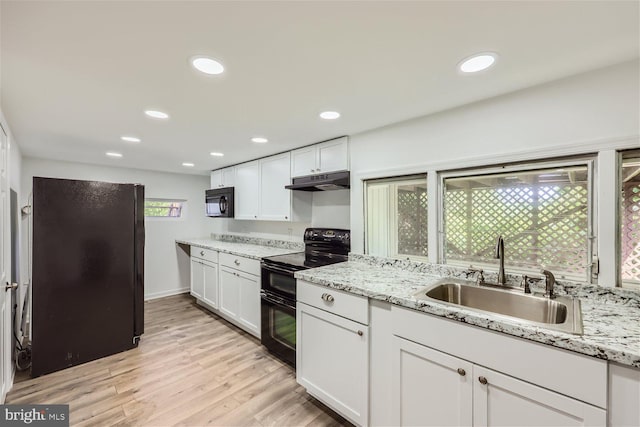 kitchen with sink, light stone counters, white cabinetry, and black appliances