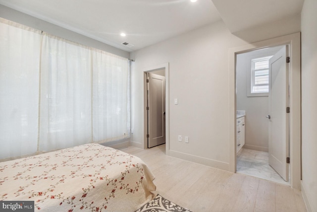 bedroom featuring connected bathroom and light wood-type flooring