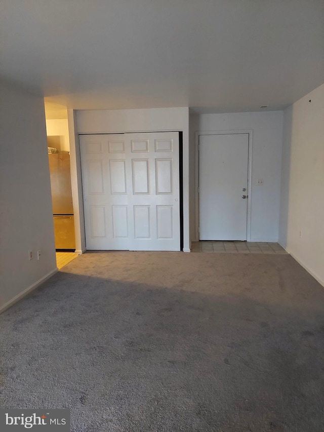 unfurnished bedroom featuring light carpet, stainless steel refrigerator, and a closet