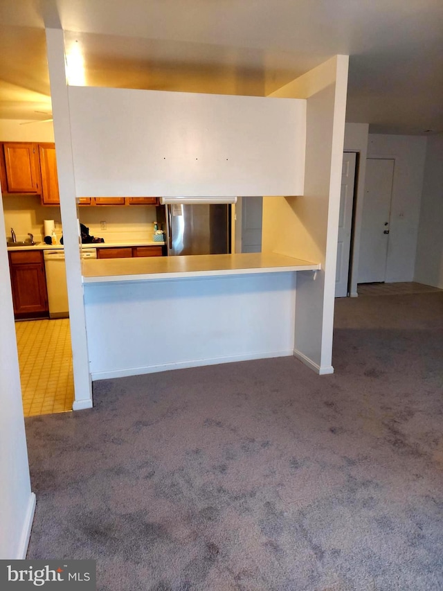 kitchen featuring kitchen peninsula, light colored carpet, and fridge