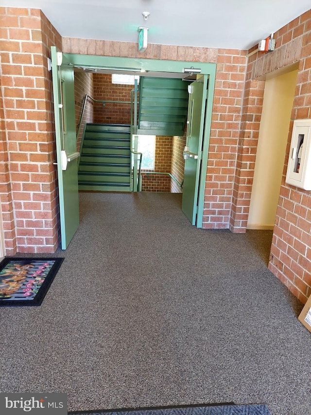 interior space featuring brick wall and dark carpet