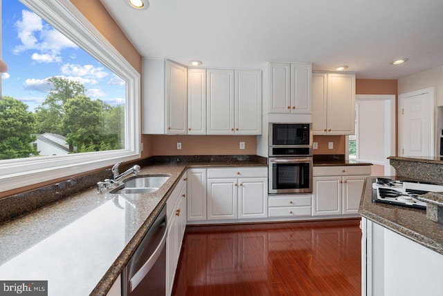 kitchen featuring sink, dark wood-type flooring, stone counters, stainless steel appliances, and white cabinets