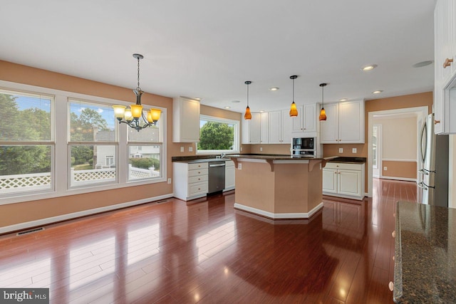 kitchen with a kitchen island, appliances with stainless steel finishes, pendant lighting, and white cabinets