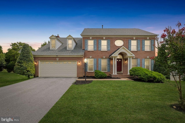 colonial-style house featuring a garage and a yard