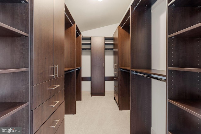 walk in closet featuring light carpet and lofted ceiling