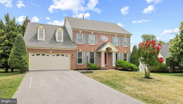 colonial inspired home featuring a garage and a front lawn