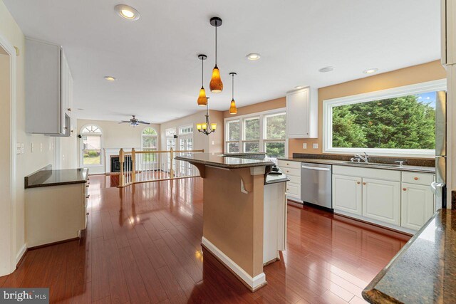 kitchen with white cabinetry, ceiling fan with notable chandelier, a center island, and stainless steel dishwasher