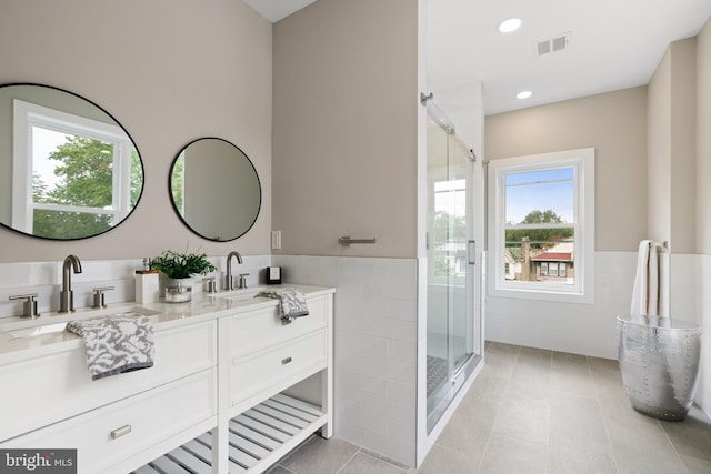 bathroom with tile patterned flooring, vanity, tile walls, and a shower with shower door