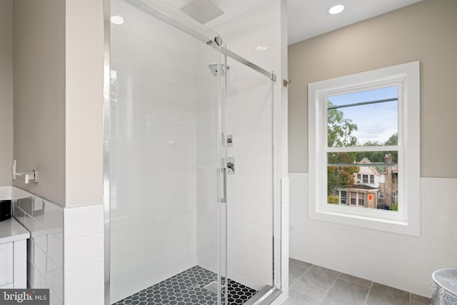 bathroom featuring a shower with shower door and tile walls