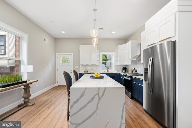 kitchen featuring blue cabinetry, a center island, tasteful backsplash, pendant lighting, and appliances with stainless steel finishes