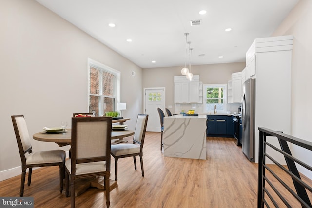 kitchen featuring pendant lighting, blue cabinets, a kitchen island, white cabinetry, and stainless steel refrigerator