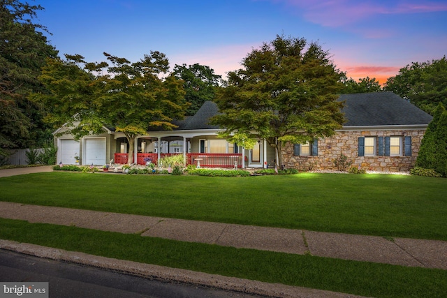 view of front of house featuring a lawn, covered porch, and a garage