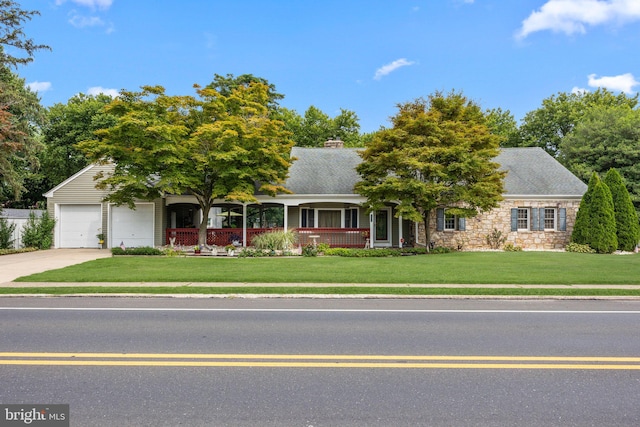 obstructed view of property featuring covered porch, a front yard, and a garage