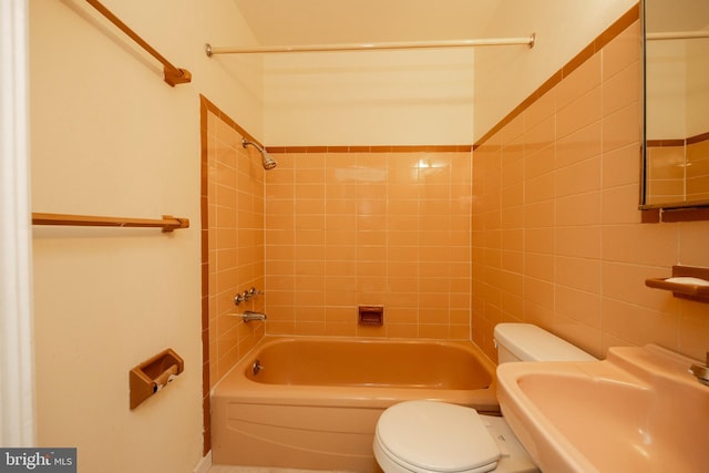 full bathroom with sink, tile walls, toilet, and tiled shower / bath