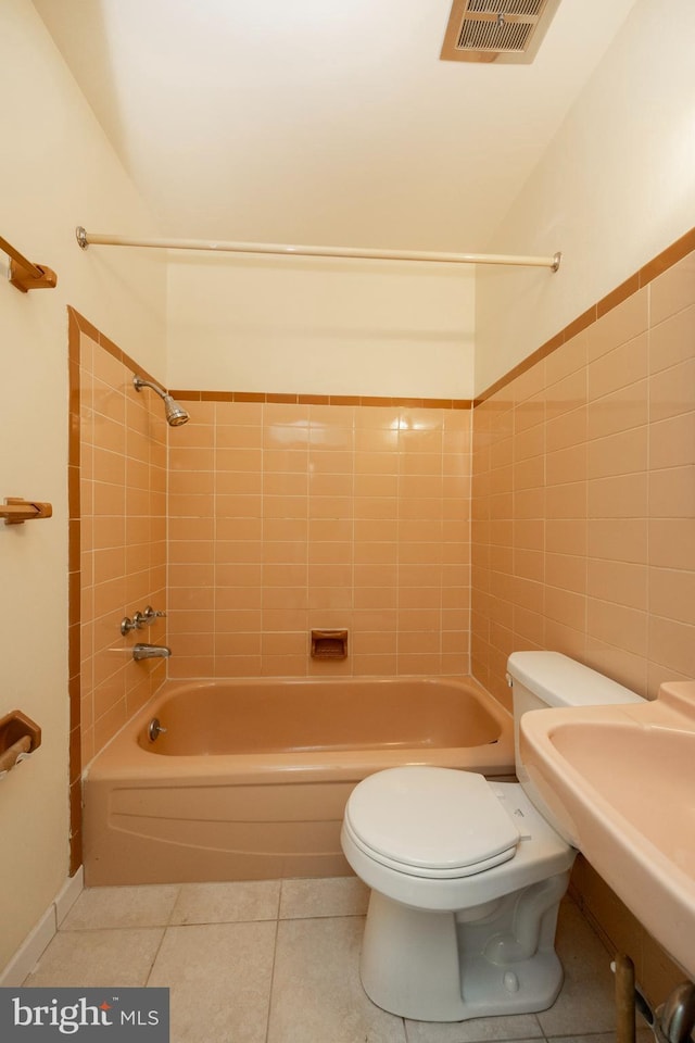 full bathroom featuring tiled shower / bath combo, tile patterned floors, sink, tile walls, and toilet