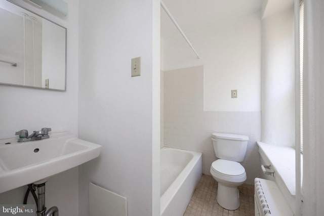 bathroom featuring toilet, tile walls, tile patterned flooring, a washtub, and radiator heating unit