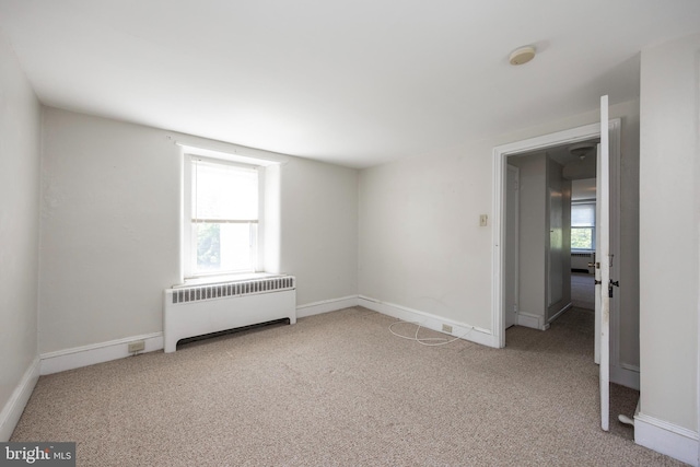 empty room with light carpet and radiator heating unit