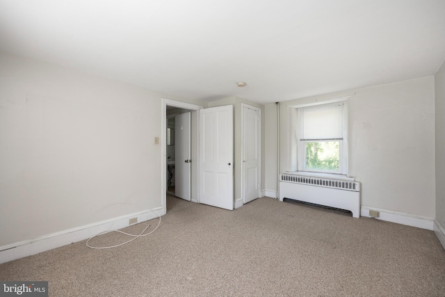 unfurnished bedroom featuring carpet floors and radiator heating unit